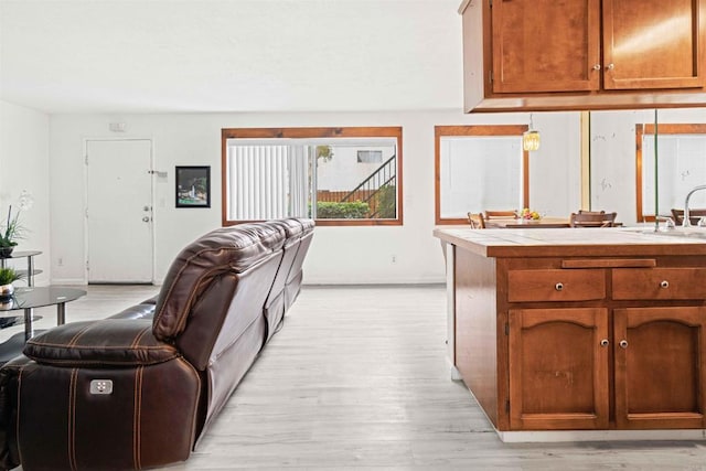 kitchen with sink, tile countertops, and light hardwood / wood-style flooring