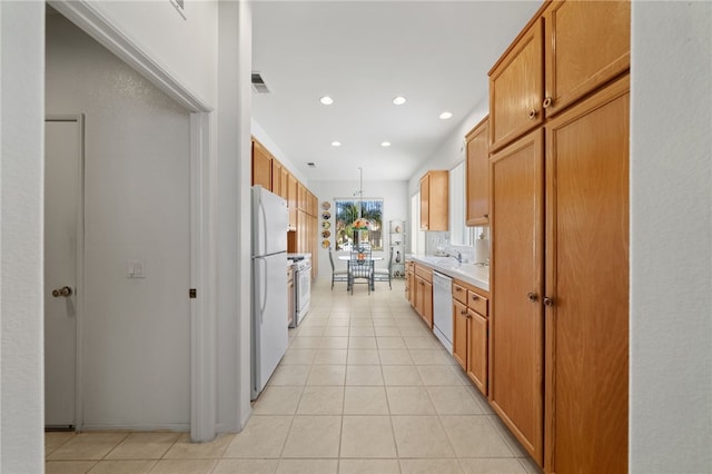 kitchen with sink, light tile patterned floors, and white appliances