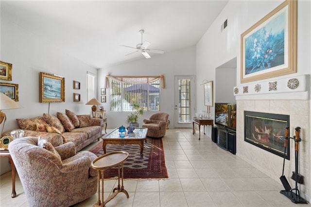 living room with a tiled fireplace, vaulted ceiling, light tile patterned floors, and ceiling fan