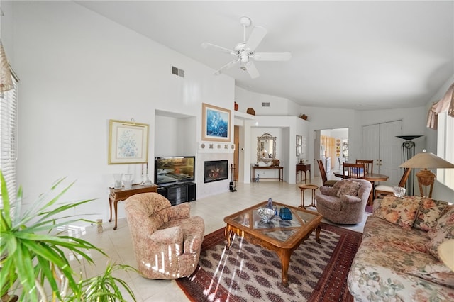 living room featuring ceiling fan, a fireplace, vaulted ceiling, and light tile patterned flooring