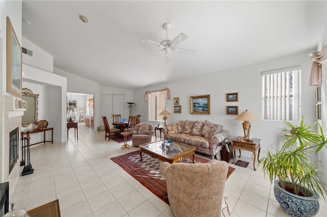 tiled living room featuring ceiling fan, a fireplace, and vaulted ceiling