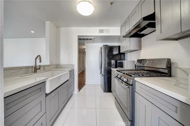 kitchen with visible vents, stainless steel microwave, range hood, gray cabinets, and gas stove