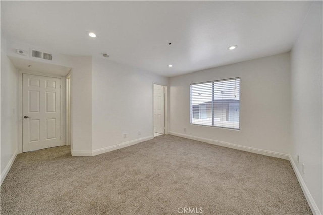 spare room featuring baseboards, recessed lighting, visible vents, and light colored carpet