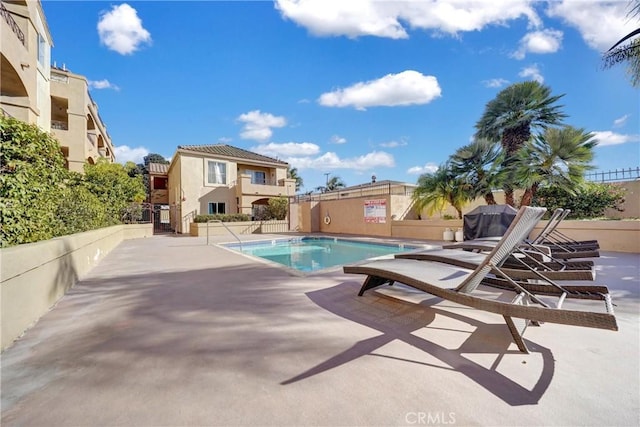 community pool with a patio area and fence