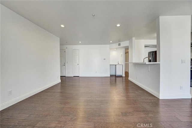 unfurnished living room with dark wood-type flooring, recessed lighting, and baseboards