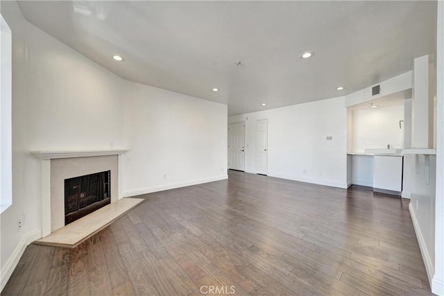 unfurnished living room featuring a fireplace, dark wood-type flooring, and recessed lighting