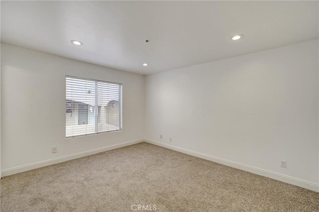 empty room featuring recessed lighting, light colored carpet, and baseboards