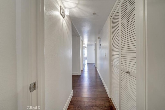 hall featuring baseboards and dark wood-style flooring