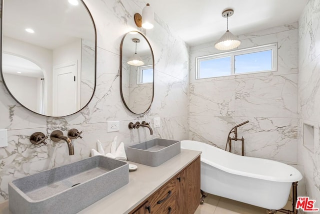 bathroom with a tub to relax in, vanity, and tile walls