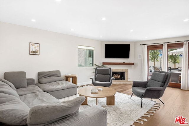 living room with a tile fireplace and light wood-type flooring