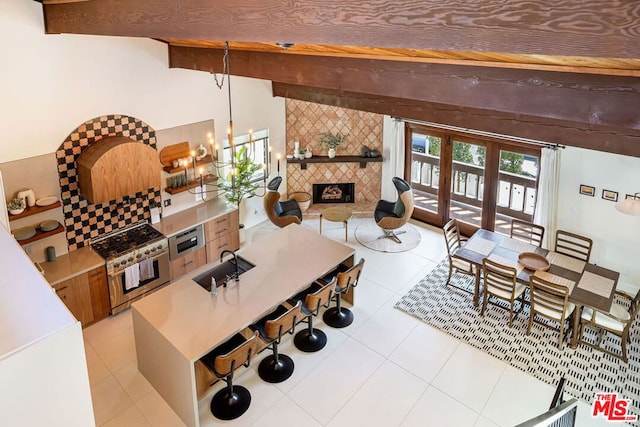 tiled living room featuring beamed ceiling, an inviting chandelier, a tiled fireplace, and sink