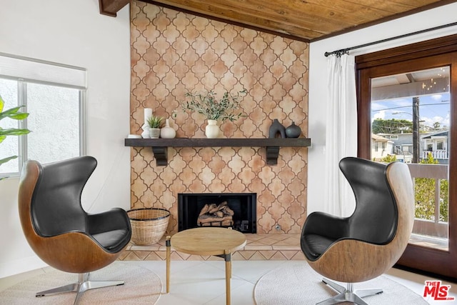 sitting room with a tile fireplace, a wealth of natural light, tile patterned floors, and wood ceiling