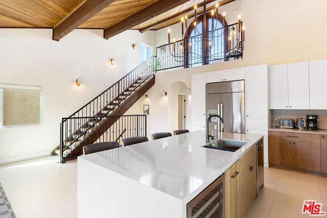 kitchen with sink, wood ceiling, a center island with sink, appliances with stainless steel finishes, and beamed ceiling