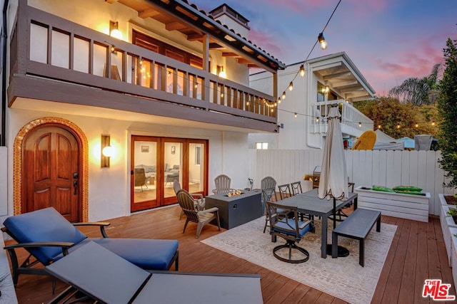 deck at dusk with french doors and an outdoor fire pit