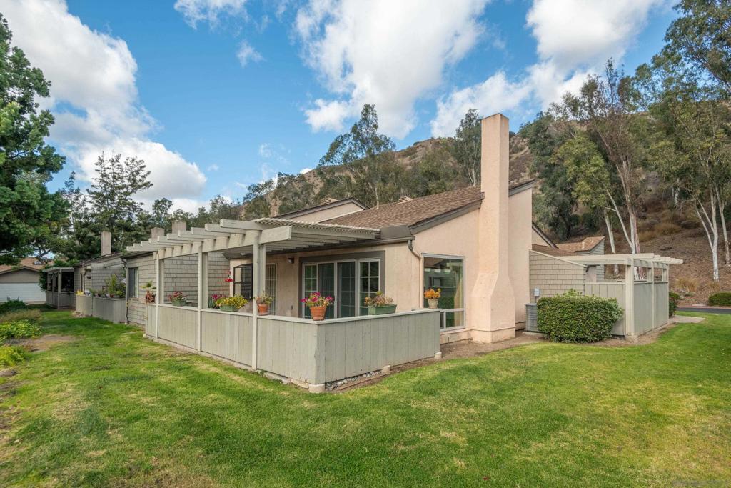 rear view of property featuring a pergola and a lawn