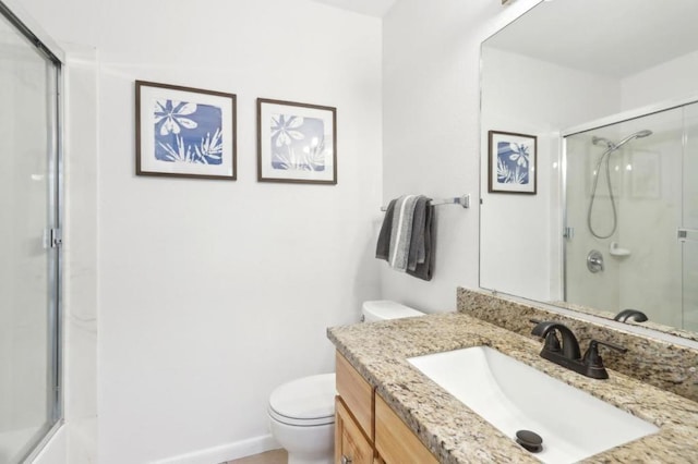 bathroom with vanity, toilet, and a shower with door