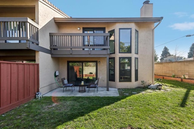 back of house featuring a balcony, a yard, and a patio