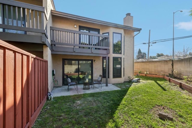 rear view of house with a yard, a patio, and a balcony