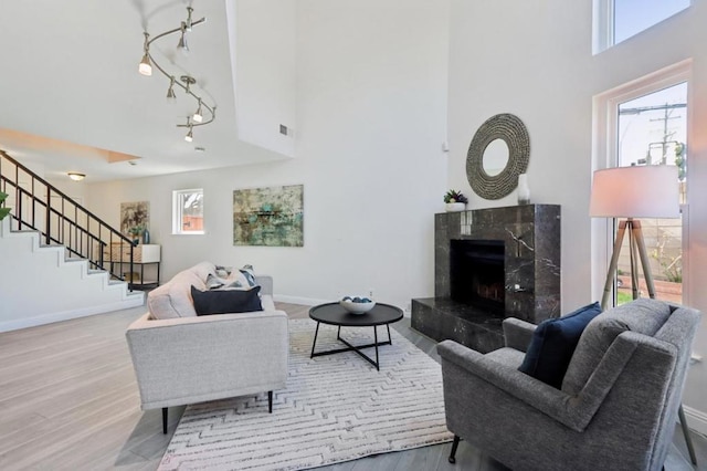 living room with a towering ceiling, a high end fireplace, and light hardwood / wood-style floors