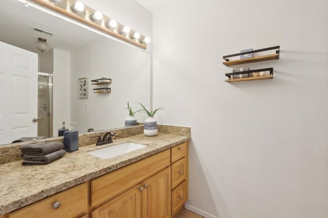 bathroom with a shower with door and vanity