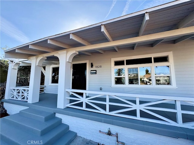 view of exterior entry featuring covered porch