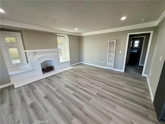 unfurnished living room with crown molding and light hardwood / wood-style floors