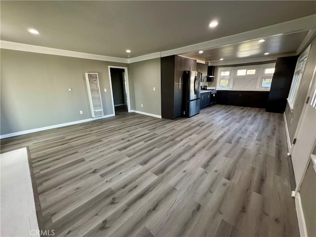 unfurnished living room featuring crown molding and light wood-type flooring