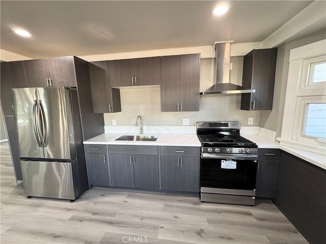 kitchen with sink, dark brown cabinetry, stainless steel appliances, wall chimney range hood, and light hardwood / wood-style flooring