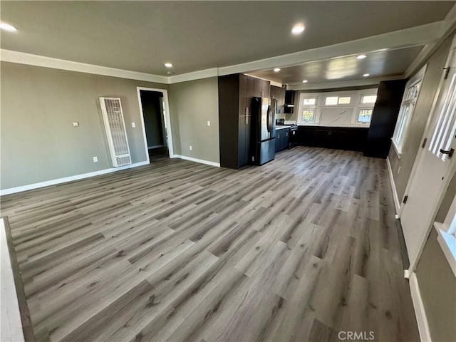 unfurnished living room featuring ornamental molding and light wood-type flooring