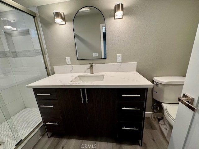 bathroom with vanity, wood-type flooring, a shower with door, and toilet