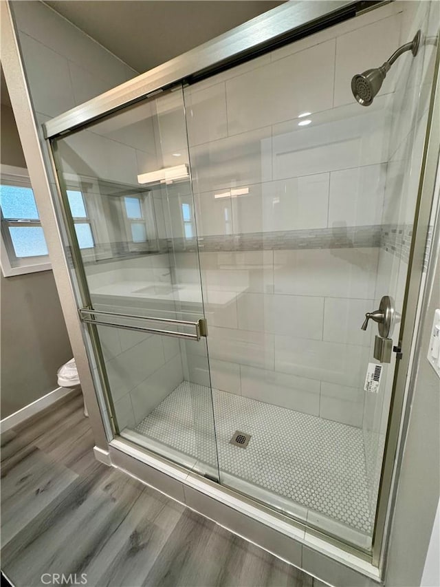 bathroom with hardwood / wood-style flooring and a shower with shower door