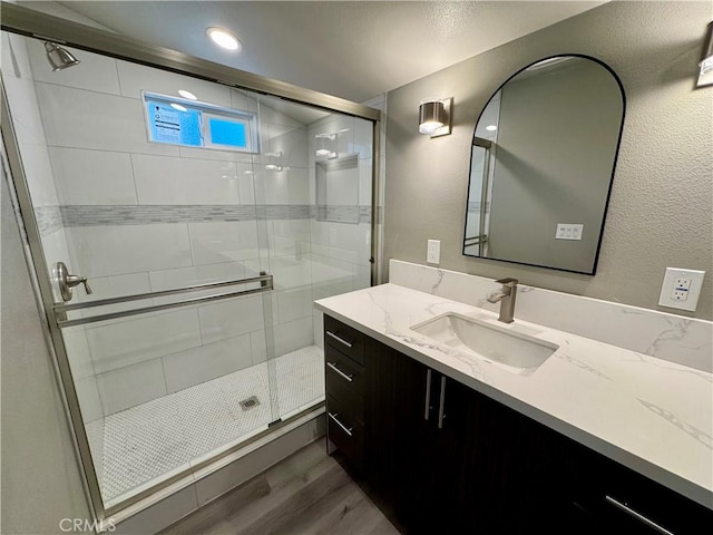 bathroom with vanity, hardwood / wood-style floors, and a shower with door