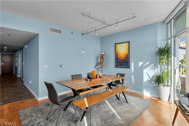 dining space with hardwood / wood-style floors and track lighting