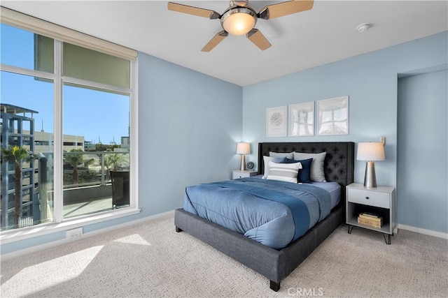 bedroom with a wall of windows, light colored carpet, and ceiling fan