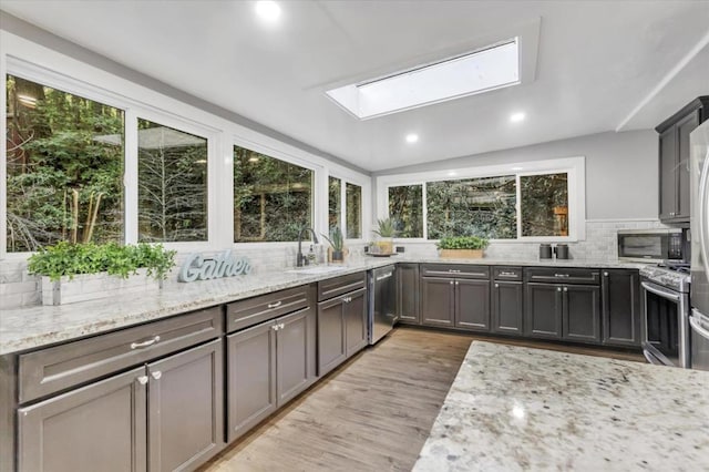 kitchen with light stone counters, stainless steel appliances, and light wood-type flooring