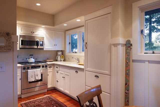 kitchen featuring sink, white cabinets, backsplash, light hardwood / wood-style floors, and stainless steel appliances