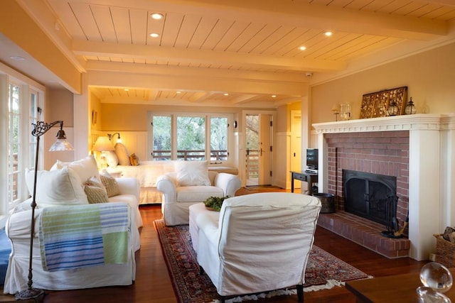 living room featuring a brick fireplace, beam ceiling, dark wood-type flooring, and wooden ceiling