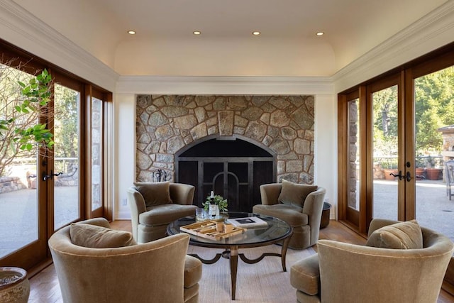 sitting room with wood-type flooring, a stone fireplace, and french doors