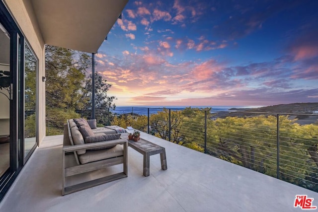 patio terrace at dusk featuring a water view, a balcony, and outdoor lounge area