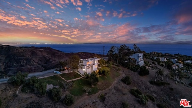 aerial view at dusk featuring a water view