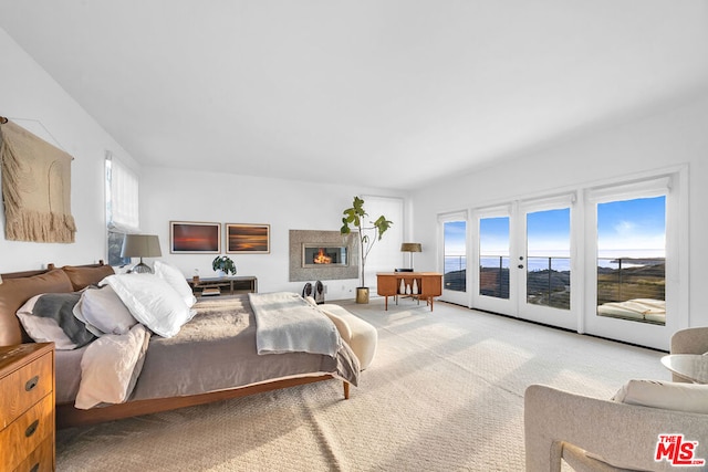 carpeted bedroom featuring a water view, access to exterior, multiple windows, and french doors