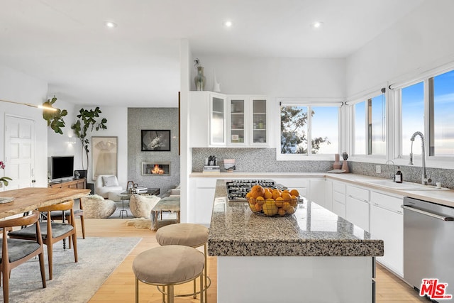 kitchen featuring sink, stainless steel appliances, a center island, a large fireplace, and white cabinets