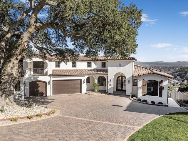 mediterranean / spanish house with a garage, a balcony, a mountain view, and french doors