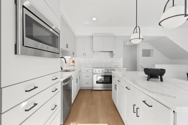 kitchen featuring sink, white cabinetry, tasteful backsplash, hanging light fixtures, and stainless steel appliances