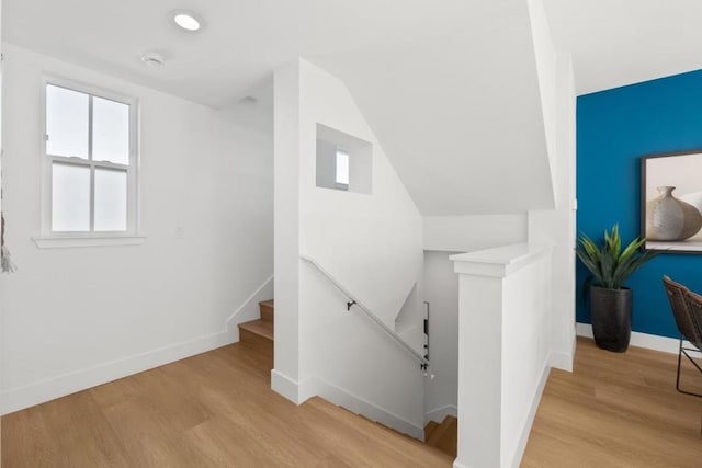 stairway with vaulted ceiling and hardwood / wood-style floors