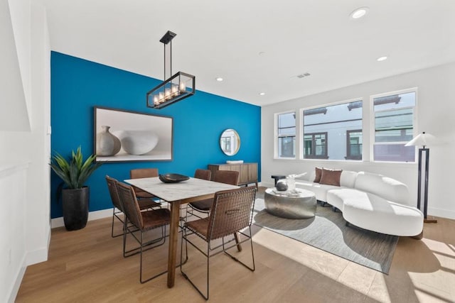 dining area with a notable chandelier and light hardwood / wood-style floors