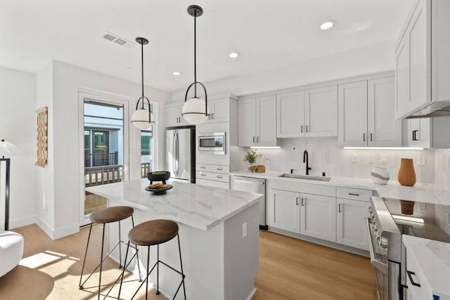 kitchen featuring stainless steel appliances, a center island, sink, and white cabinets