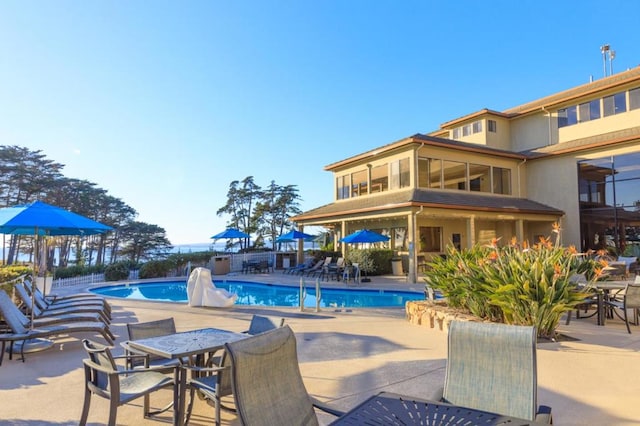 view of swimming pool featuring a sunroom and a patio