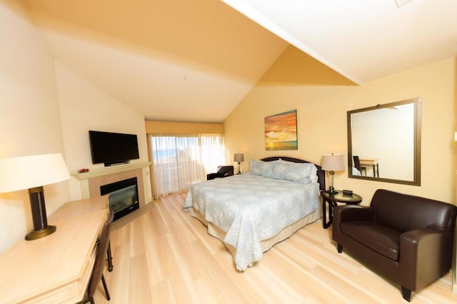 bedroom featuring a fireplace, vaulted ceiling, and light wood-type flooring