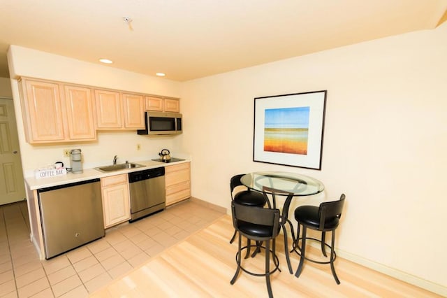 kitchen with light tile patterned flooring, appliances with stainless steel finishes, light brown cabinetry, and sink